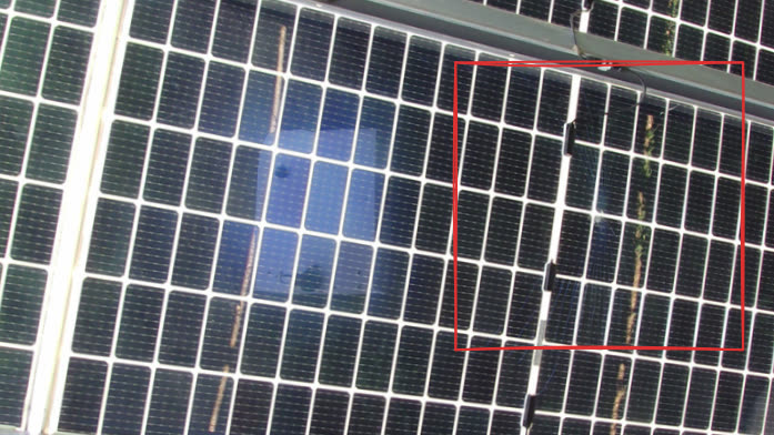 Back of a utility-scale solar module with a region of cracked glass marked by the robot's detection box